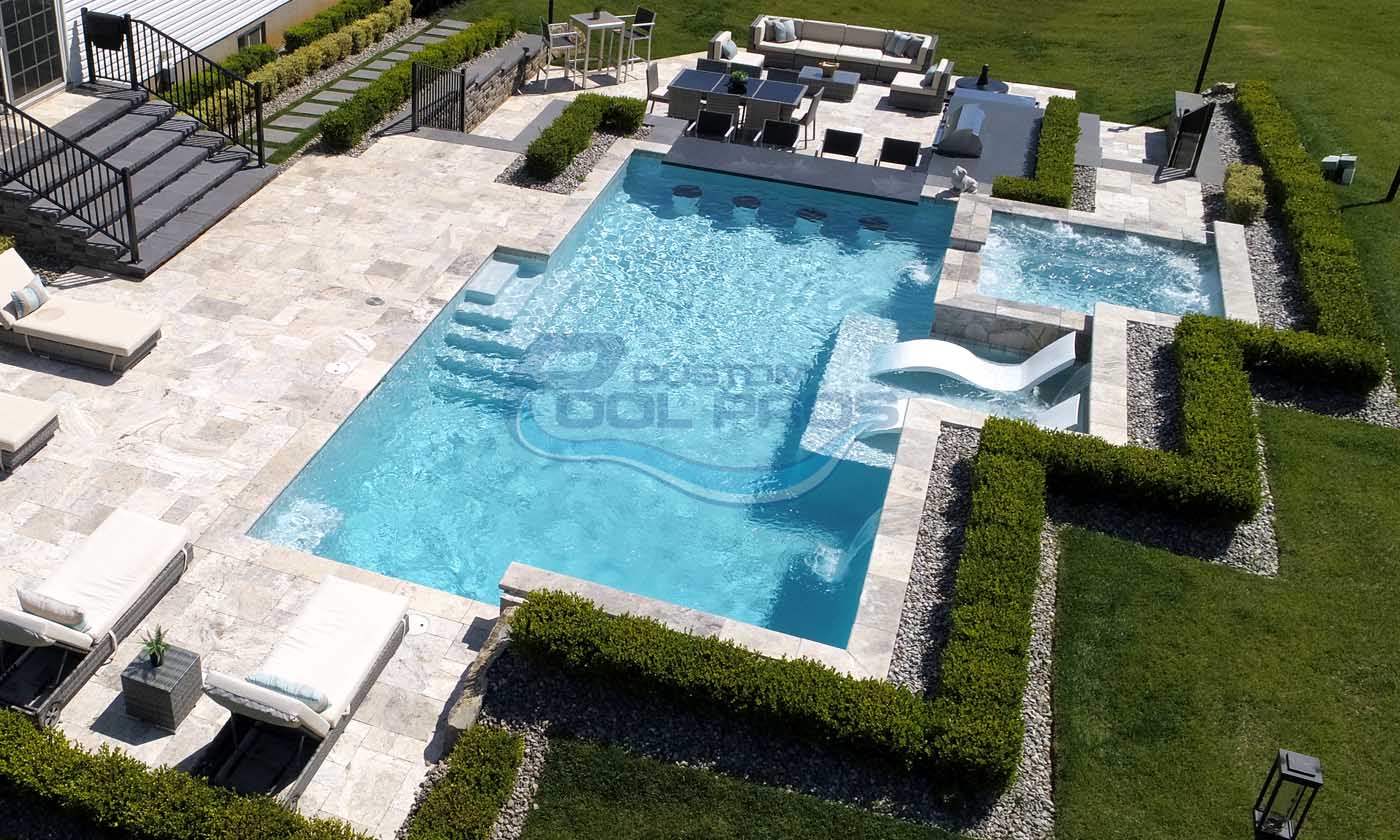 Luxurious outdoor swimming pool with a water slide, surrounded by manicured hedges and a spacious patio area, perfect for relaxation and entertaining.