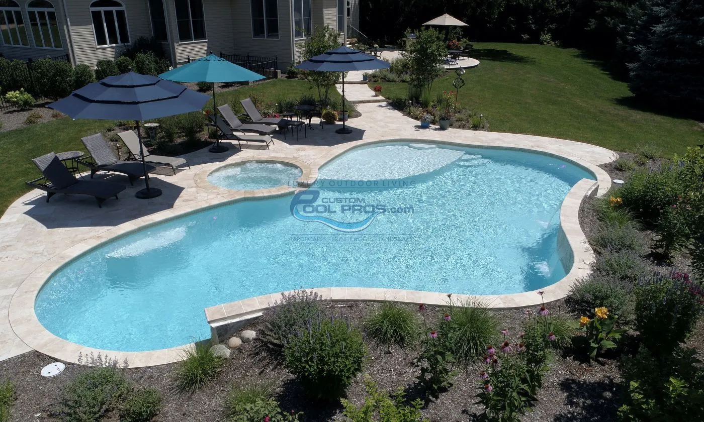 freeform style inground gunite concrete pool installation with light blue turquoise water, pool deck with anti-slip travertine tile, inground swimming pool